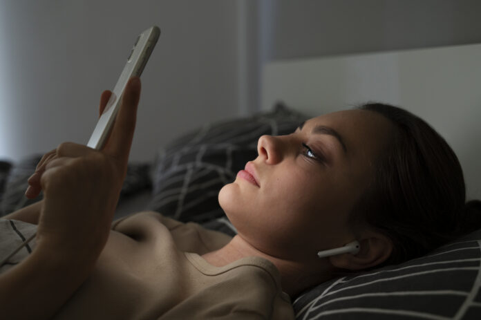 mulher com celular na cama
